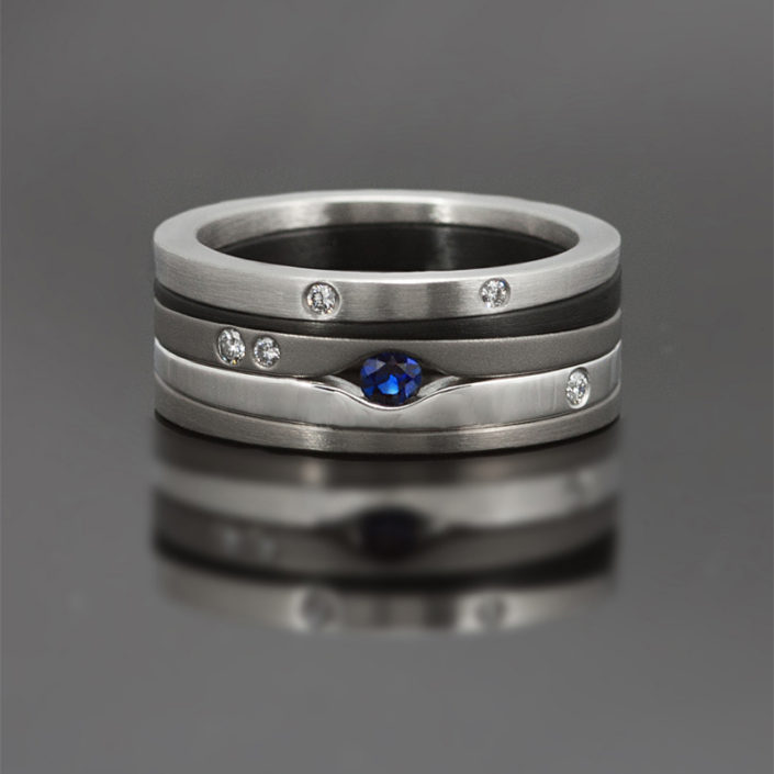 Ring gemaakt van zirkonium, witgoud, edelstaal en titanium, bezet met een blauwe saffier en witte diamanten.